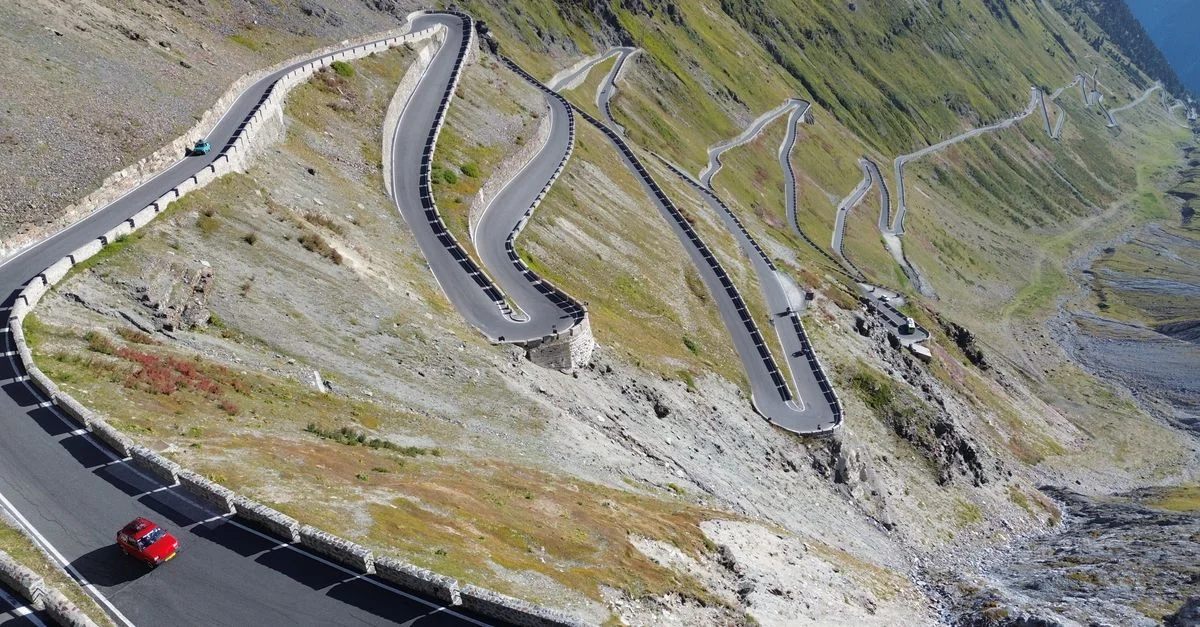 Vue aérienne de la route sinueuse du col du Stelvio dans les Alpes italiennes, avec des voitures.