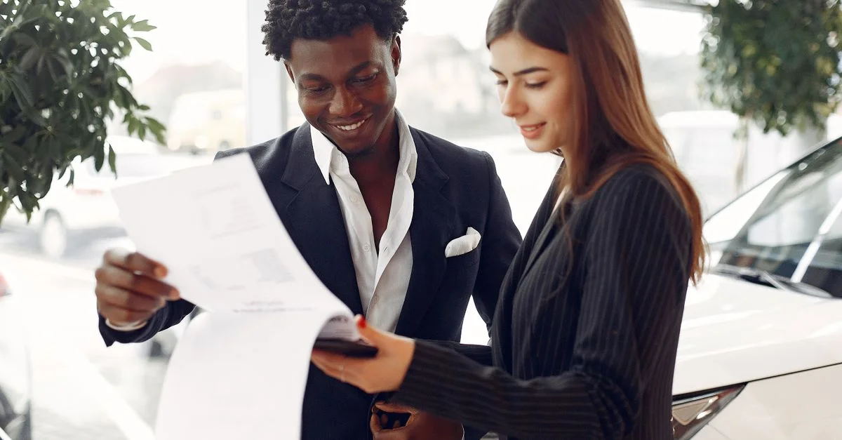 Professionnels du secteur discutant de documents dans un concessionnaire automobile