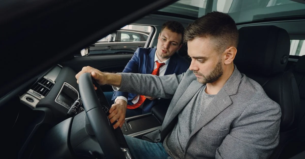 Un vendeur présente les caractéristiques d'une voiture à un acheteur potentiel dans une salle d'exposition.