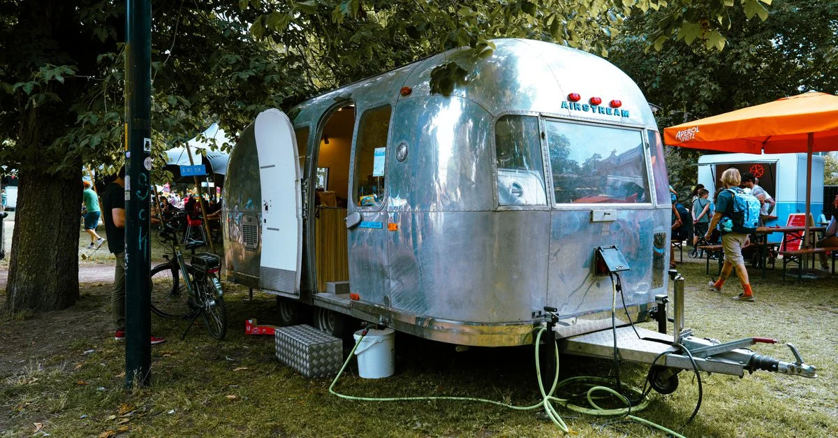 Caravane Airstream classique garée à l'extérieur lors d'un événement festival animé.