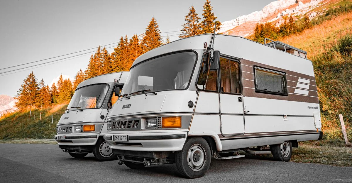 Vans de camping classiques stationnés dans un cadre pittoresque de montagnes durant l'heure dorée.