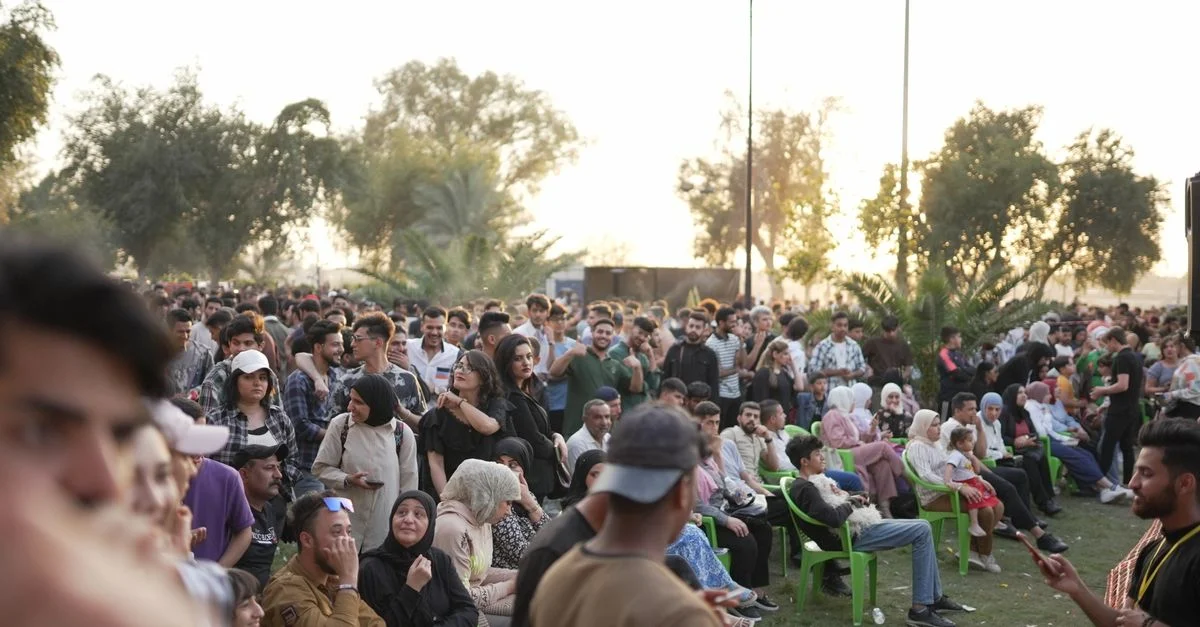 Une foule diversifiée profitant d'un concert en plein air au coucher du soleil, créant une atmosphère vibrante et animée.