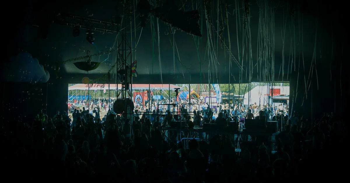 Une foule profitant de la musique live sur une scène de festival en plein air colorée.