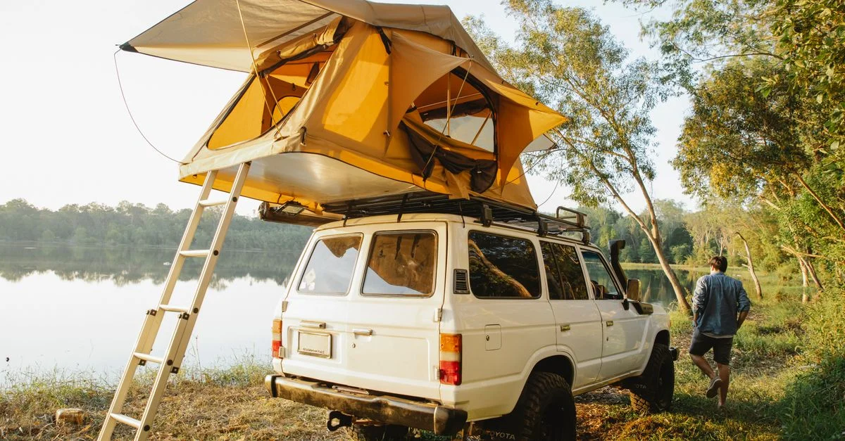Explorez la nature avec une tente de toit sur un véhicule 4x4 au bord d'un lac paisible.