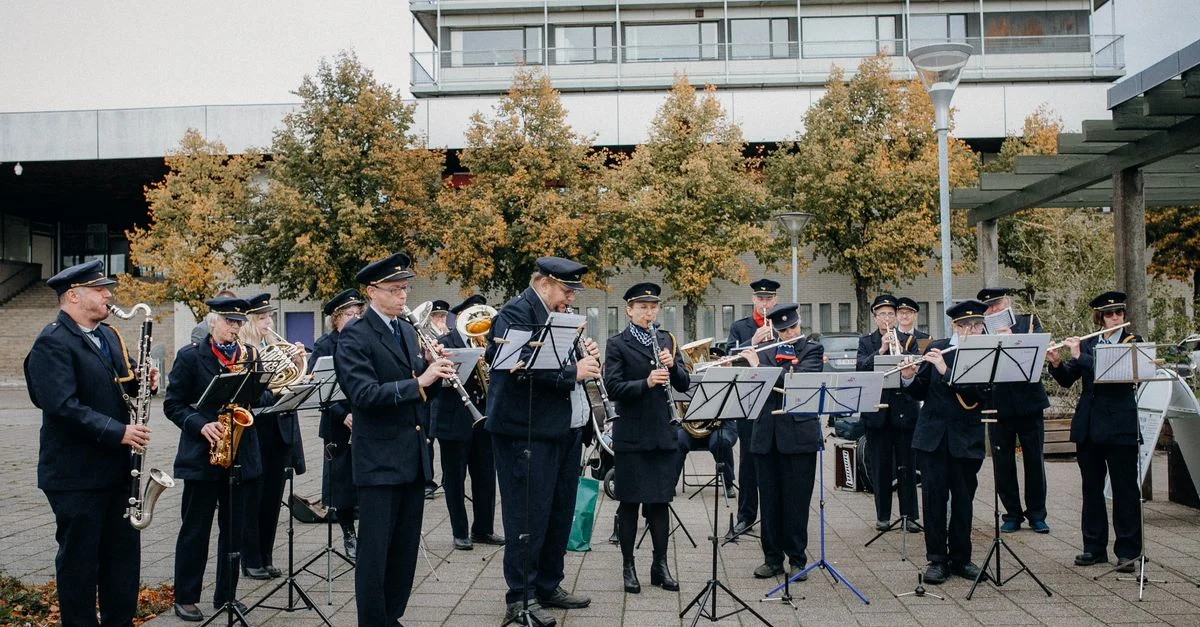 Une performance en extérieur d'une fanfare en uniformes, jouant divers instruments.