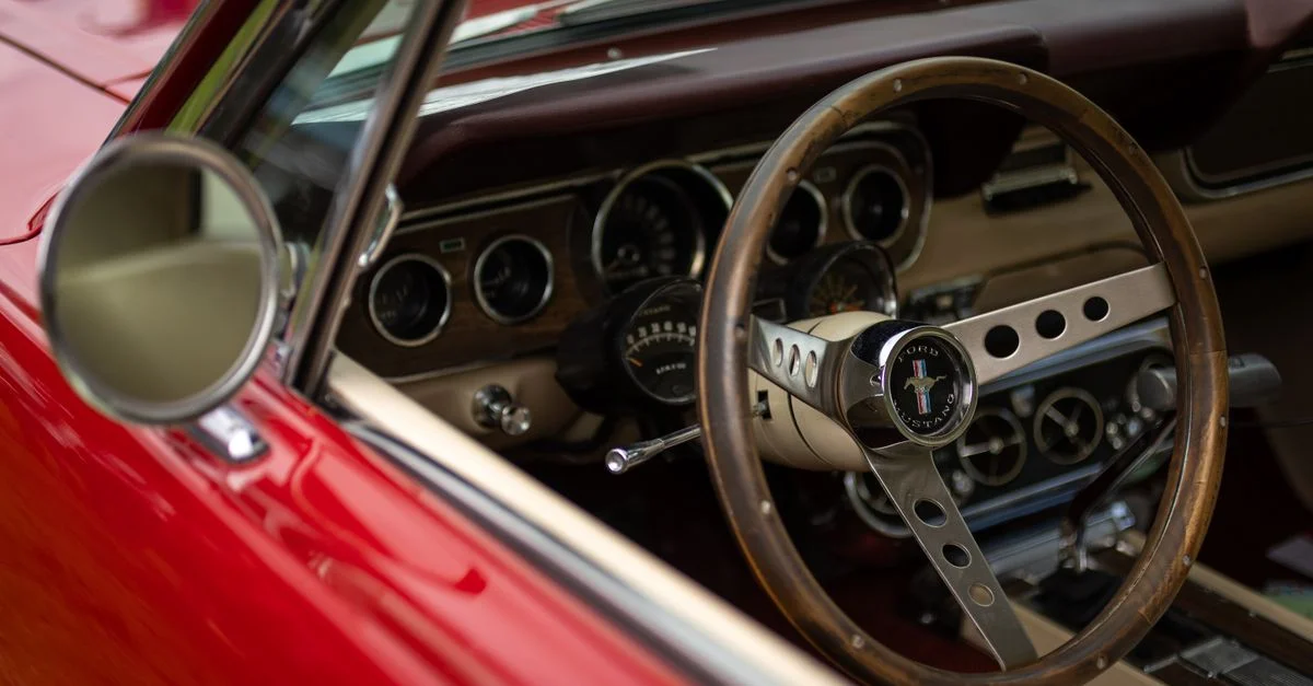 Une vue rapprochée de l'intérieur d'une voiture classique mettant en avant un volant vintage et un tableau de bord.