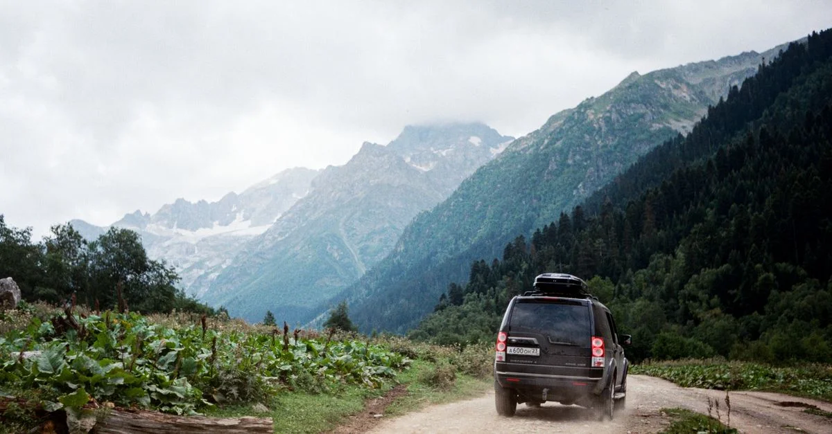 Un SUV roulant sur un chemin accidenté à travers les magnifiques montagnes du Caucase en Russie.